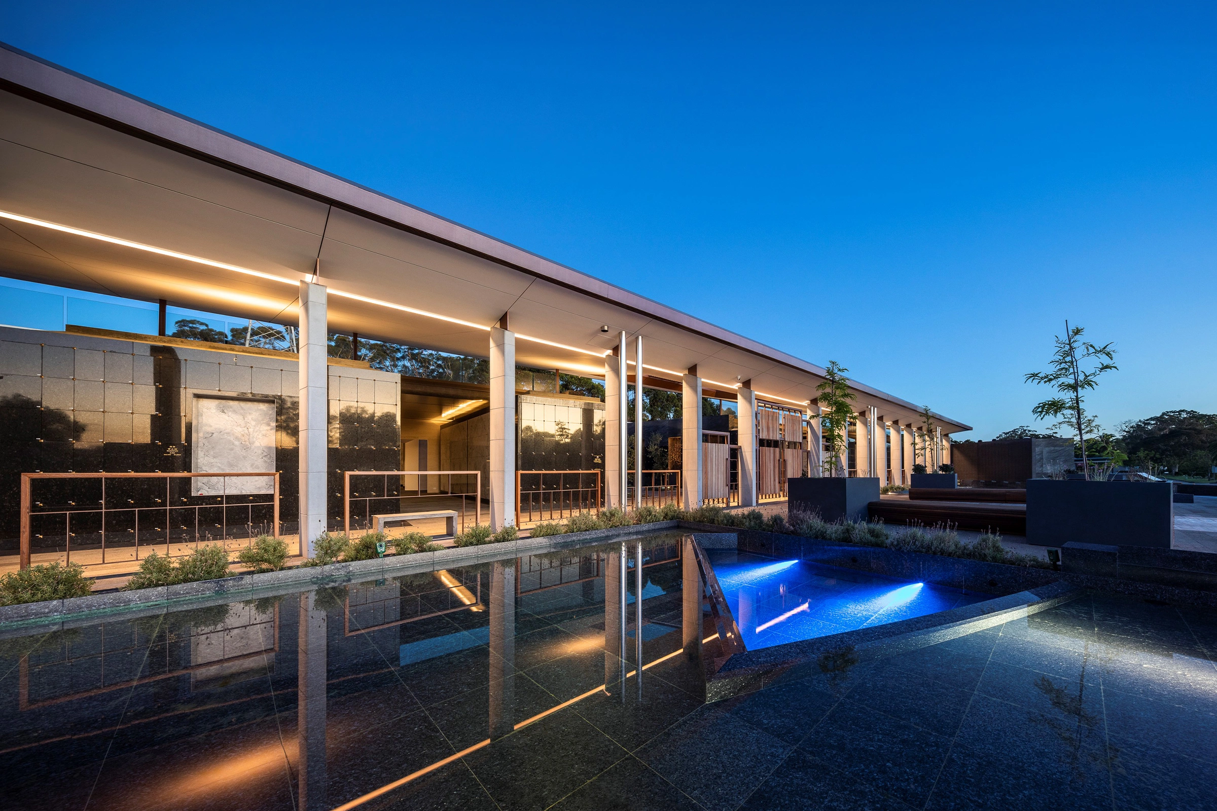 Mausoleum of the Holy Way at Macquarie Park Cemetery in northern Sydney, designed by Wetherill Architects, showing columbaria at dusk with sensory reflection pool