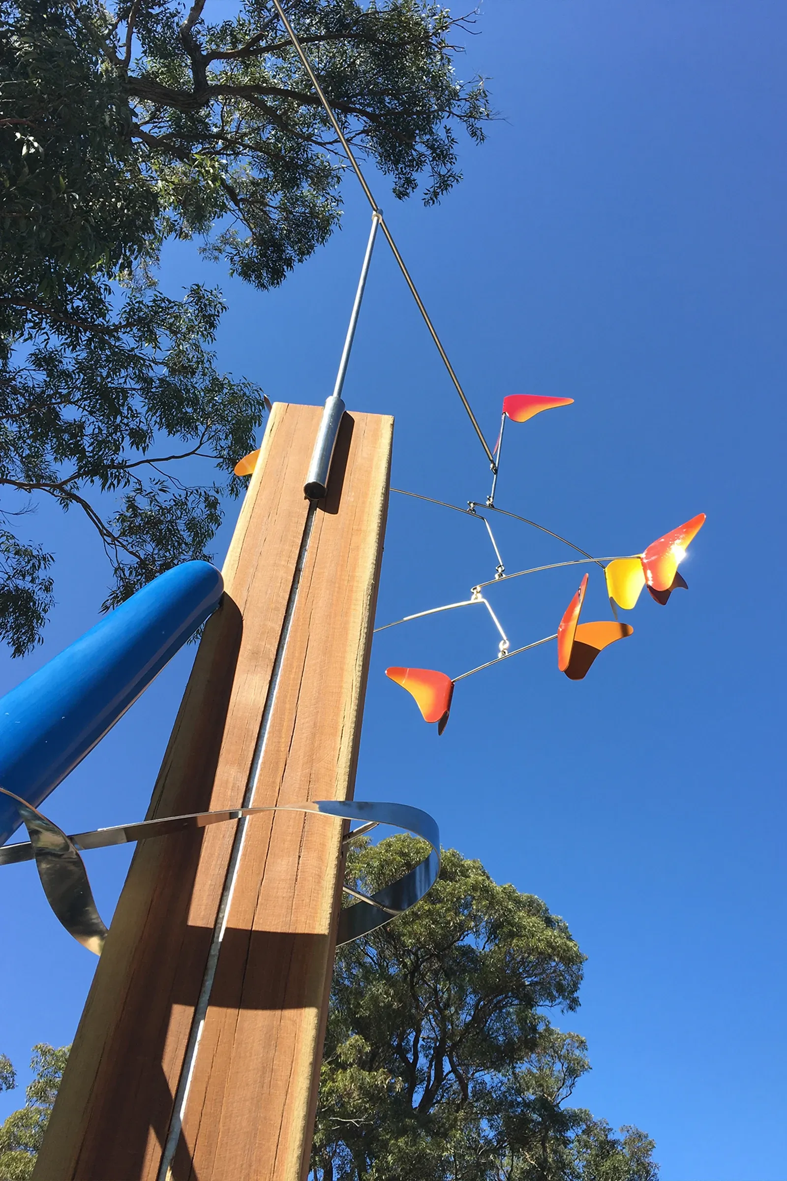 Hope & Sanctuary public artwork with sculptural timber post and colourful suspended butterflies contrasting against blue sky