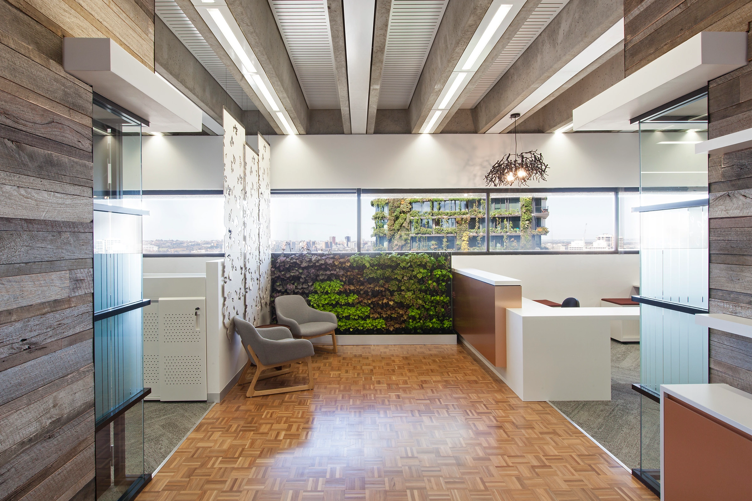 Interior design of UTS Building 1 Levels 20–21 office reception space, with green wall, parquet flooring and refurbished exposed concrete ceiling