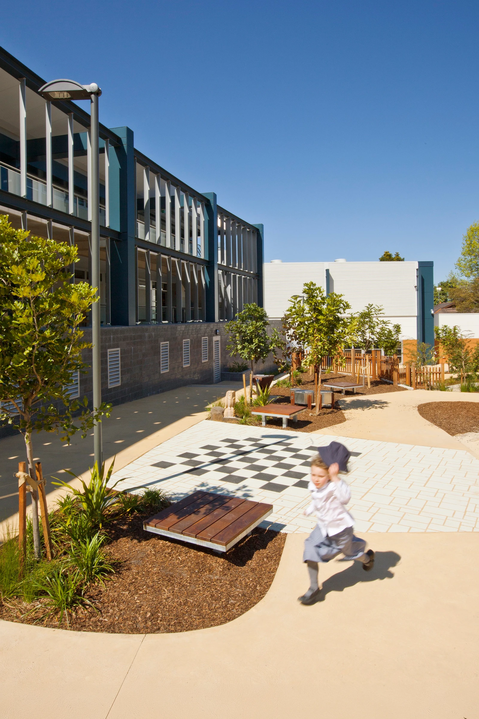 Student running through Redlands Junior School in Cremorne, Sydney, designed by Wetherill Architects, with vertical sunshading louvres and outdoor teaching and learning areas